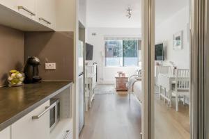 a kitchen with white cabinets and a dining room at Cosy Inner-city Hideaway in the Heart of Annandale in Sydney