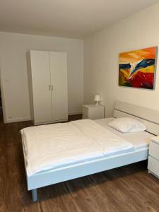 Un dormitorio con una cama blanca y una pintura en la pared en Zimmer mit geteiltem Bad & Küche, en Brugg