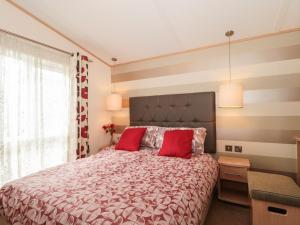 a bedroom with a large bed with red pillows at Swallows Lodge in Shepton Mallet