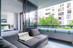 een woonkamer met een bank en een groot raam bij 'Eastgardens Splendour' Two-storey Style with Pool in Sydney