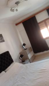 um quarto com uma cama branca e uma janela em Appartement centre ville em Larache