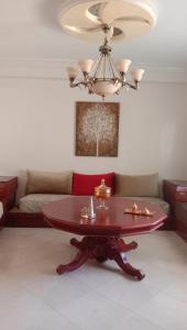 uma sala de estar com uma mesa e um sofá em Appartement centre ville em Larache