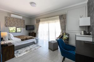 a bedroom with a bed and a desk and a window at The African Penguin Guesthouse in Pretoria
