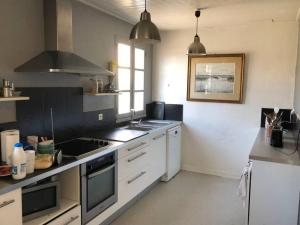 uma cozinha com armários brancos e um forno com placa de fogão em Belle maison vendéenne em Jard-sur-Mer