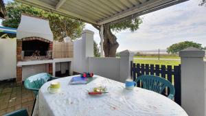 a table and chairs on a patio with a fireplace at Paradise Beach Cottage in Jeffreys Bay