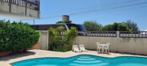 a house with a swimming pool with two chairs and a fence at Hotel Praia 2000 in Fortaleza