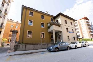 zwei Autos, die vor einem gelben Gebäude geparkt sind in der Unterkunft New apartment Trento (parking) in Trient