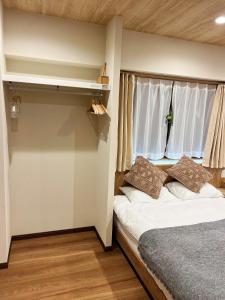 um pequeno quarto com uma cama e uma janela em akihabara k em Tóquio