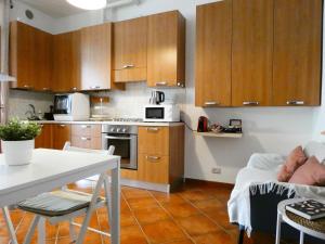 eine Küche mit Holzschränken sowie einem weißen Tisch und Stühlen in der Unterkunft Baciati dal Sole-Self check-in in San Pellegrino Terme