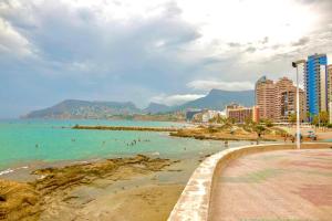 a beach with people in the water and buildings at Hernando II in Calpe