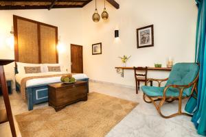a bedroom with a bed and a table and a chair at Club Mango Resort in Kalpitiya