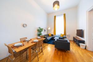 a living room with a table and chairs and a couch at Shining bright two bedroom apt next to Andrassy ave in Budapest