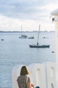 a woman sitting on a chair watching boats in the water at AVANTI Lifestyle Hotel - Only Adults in Corralejo