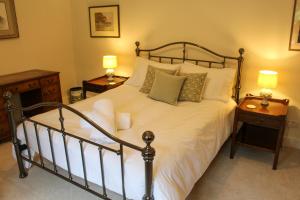 1 dormitorio con 1 cama blanca grande y 2 lámparas en Hornbeam Cottage en Kirtlington