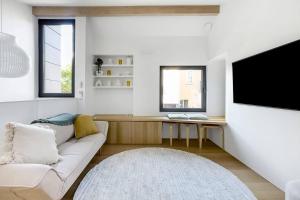 Il comprend un salon blanc doté d'un canapé et d'une télévision. dans l'établissement 'The Honeycomb' Experience Passive Nordic Design, à Sydney