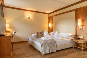 une chambre d'hôtel avec un lit et une télévision dans l'établissement Alpin & Vital Hotel La Perla, à Ortisei