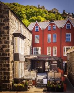 a row of red buildings with tables and chairs in a courtyard at The Fanny Talbot in Barmouth