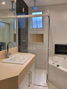 a bathroom with a sink and a glass shower door at CARIBONI in Guarujá