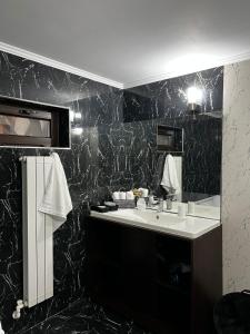La salle de bains est pourvue d'un lavabo et d'un mur en marbre noir. dans l'établissement Casa moderna in Mineri, à Mineri