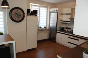 a kitchen with white cabinets and a clock on the wall at Hotelik Manhatan in Radzyń Podlaski