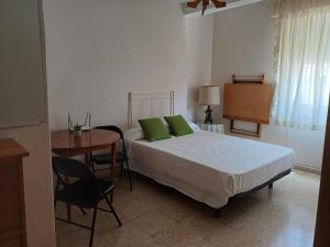 a bedroom with a bed with green pillows and a table at Apartamento Grande Subida San Diego Centro Ciudad in Cartagena