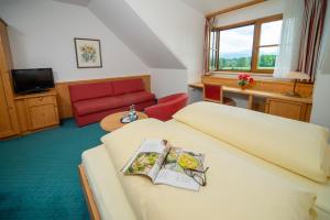 ペンツベルグにあるLandhotel Hoisl-Bräuのベッドと赤いソファが備わるホテルルームです。