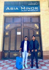 deux hommes debout devant un bâtiment avec une valise dans l'établissement Asia Minor, à Samarcande