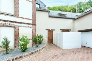 a brick house with a white refrigerator in a driveway at La Risle - Appartement spacieux in Brionne