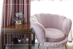 a pink chair sitting next to a wooden table at Boutique & Spa Hotel Heaven in Velingrad
