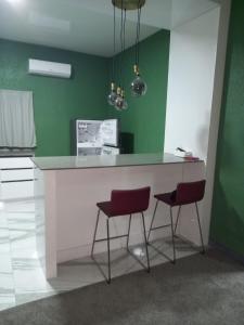 a kitchen with a white counter and two red stools at Augi's Rental 