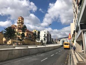 a yellow van driving down a city street with buildings at Casa Primavera - renovated duplex in city centre in Funchal
