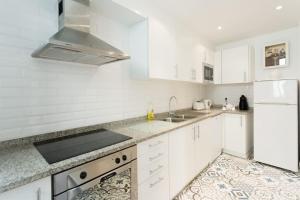 a white kitchen with a sink and a refrigerator at Casa Primavera - renovated duplex in city centre in Funchal