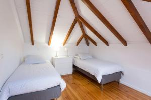 two beds in a room with white walls and wooden ceilings at Casa Primavera - renovated duplex in city centre in Funchal