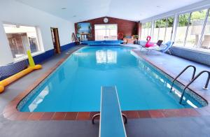 a large swimming pool with blue water in a building at Luxury property - Swimming Pool, Games Room & Hot Tub in Usk