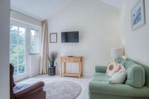 a living room with a green couch and a tv at Caradog - 1 Bedroom - St Ishmaels in Saint Ishmaels