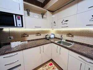 a kitchen with a sink and a microwave at 3BD Apartment in a family house with garden view in Cairo