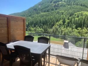 een tafel en stoelen op een balkon met een berg bij Serre chevalier, Chantemerle, pied des pistes et du bike Park in Saint-Chaffrey