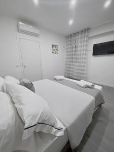 um quarto branco com 2 camas e uma janela em Capodichino Apartment 127 - 20 em Nápoles