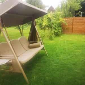 a porch swing with an umbrella in a yard at Rooms in Vilnius in Vilnius