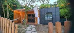 a black tiny house with a fence and lights at Kub Baile Govora in Băile Govora