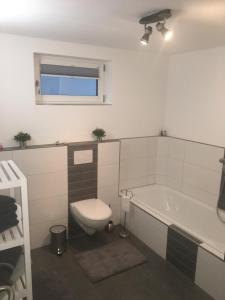 ein Badezimmer mit einem WC und einer Badewanne in der Unterkunft Peter's Ferienwohnung im Souterrain in Neuried
