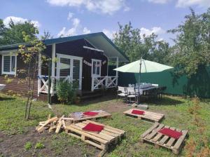 ein Haus mit einem Tisch, Stühlen und einem Sonnenschirm in der Unterkunft Садиба Герасімових in Kamjanez-Podilskyj