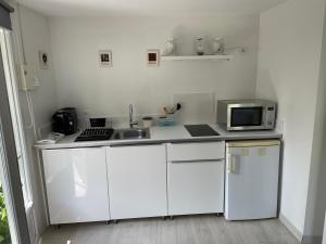a white kitchen with a sink and a microwave at Entre bassin et forêt in La Teste-de-Buch