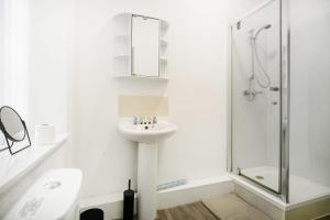 a white bathroom with a sink and a shower at Spacious 5-Bed Flat in Stockton, Sleeps 9 in Stockton-on-Tees