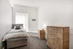 a bedroom with a bed and a wooden dresser at Spacious 5-Bed Flat in Stockton, Sleeps 9 in Stockton-on-Tees