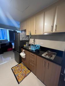a kitchen with wooden cabinets and a black refrigerator at One Palmtree Villas Airport Condo in Manila
