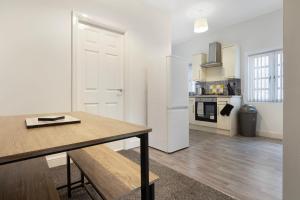 a kitchen with a wooden table and a kitchen with a refrigerator at Warm & Inviting 4-Bed on Church Road, Sleeps 4 in Stockton-on-Tees