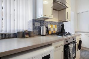 a kitchen with white cabinets and a counter top at Warm & Inviting 4-Bed on Church Road, Sleeps 4 in Stockton-on-Tees