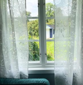 una ventana con cortinas blancas y un sofá verde en Stuga i Vomb en Veberöd