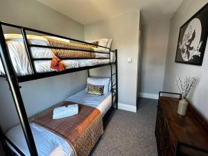 a bedroom with two bunk beds and a dresser at GREAT LOCATION! 4 bed house with garden & parking - Parkstone House in Parkstone